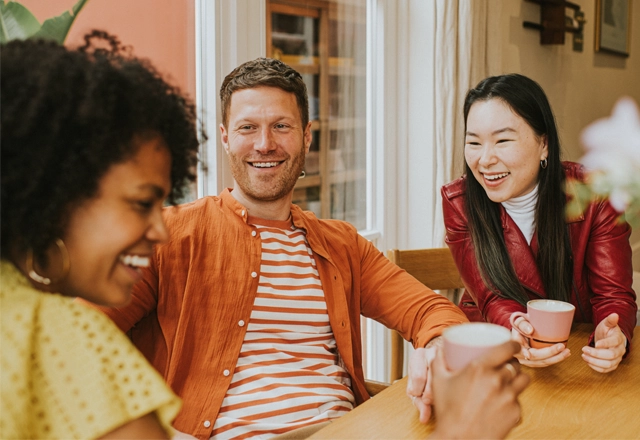 three people sitting a table smiling..
