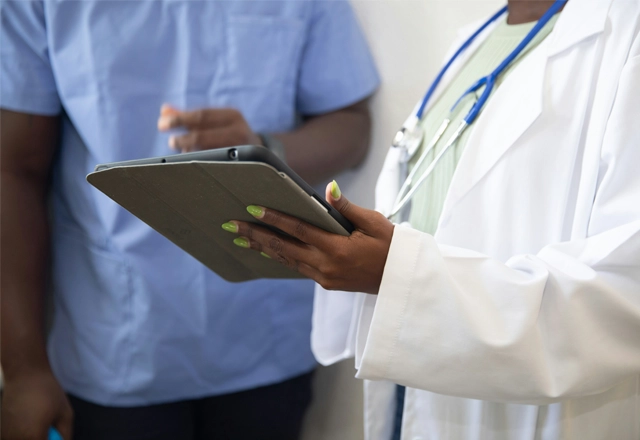 a doctor showing a patient something on a tablet, middle body shot, no faces