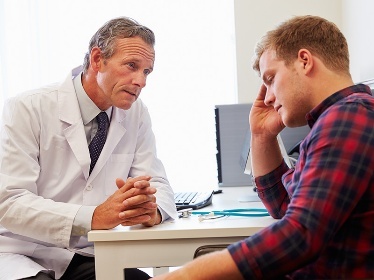 A doctor talking with a person who looks worried.