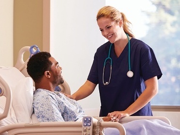A health provider standing near a patient in a hospital.